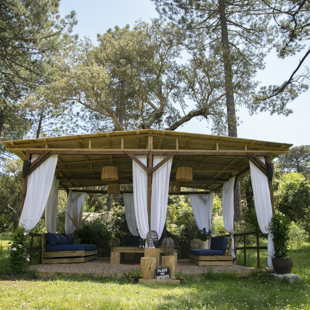 - un pavillon en bois avec des rideaux blancs et des chaises bleues dans l'établissement Domaine Authentique de Rose, à Porto-Vecchio