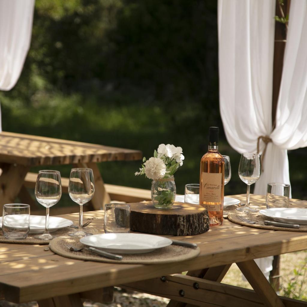 - une table en bois avec des verres et une bouteille de vin dans l'établissement Domaine Authentique de Rose, à Porto-Vecchio