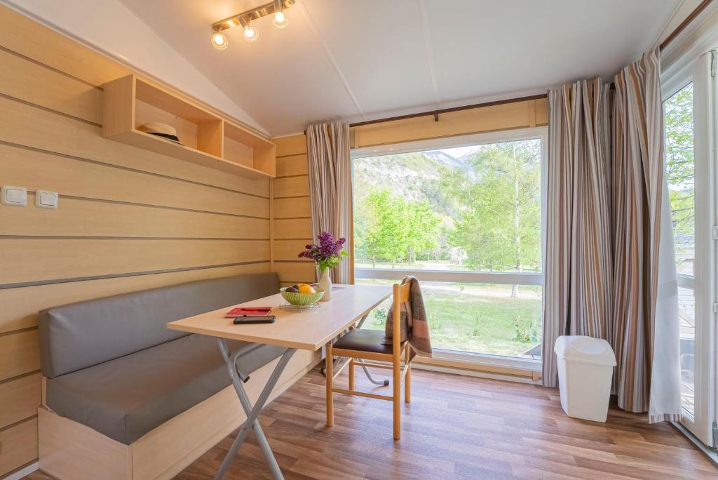 une chambre avec une table, un banc et une fenêtre dans l'établissement Camping New Rabioux, à Châteauroux-les-Alpes