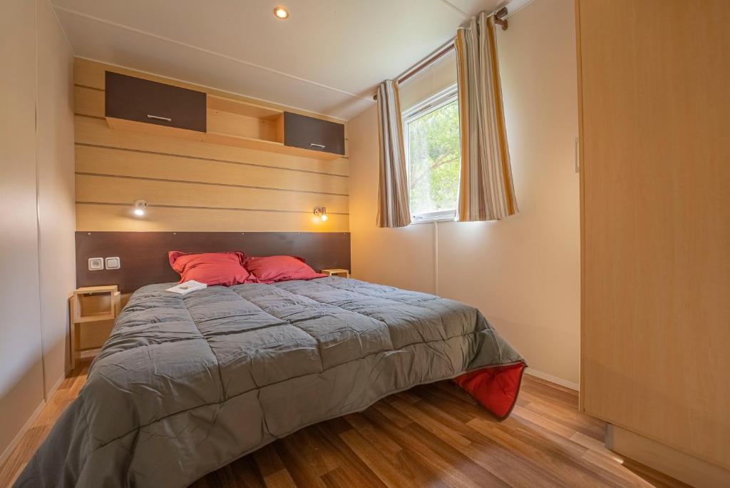 une chambre avec un lit avec des oreillers rouges et une fenêtre dans l'établissement Camping New Rabioux, à Châteauroux-les-Alpes