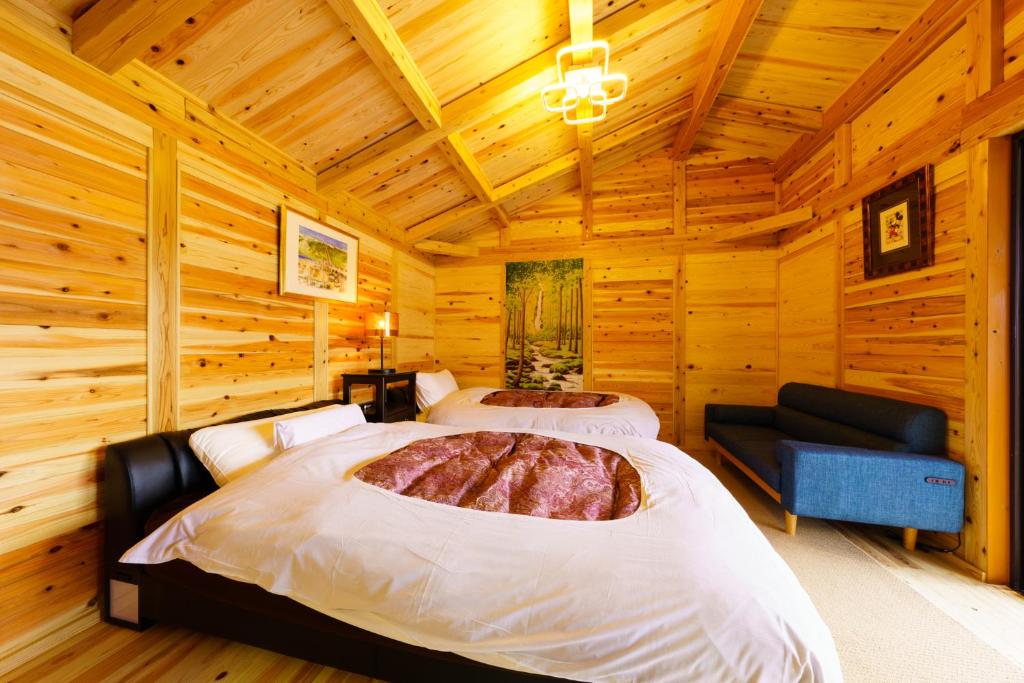 une chambre avec deux lits dans une cabane en rondins dans l'établissement Yufuin-Sanso Waremokou, à Yufu