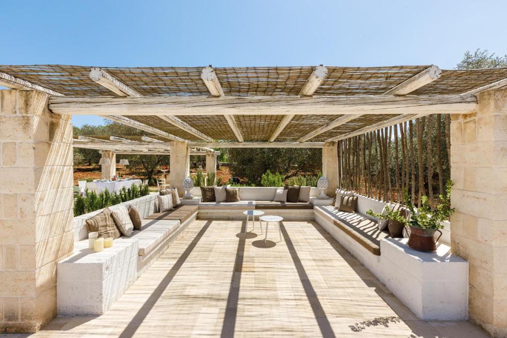 une terrasse avec des canapés et une pergola dans l'établissement Lamia del Bosco con Piscina, à Ostuni