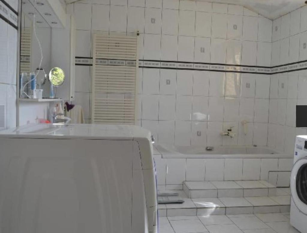 La salle de bains blanche est pourvue d'une baignoire et d'un lave-linge. dans l'établissement Gîte à la Ruelle "Pierre et Mamie" !, à Savignac-de-Miremont