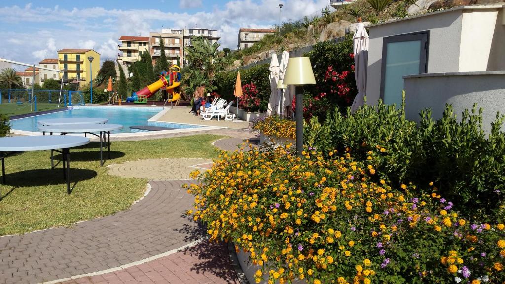 un jardin avec un billard, des tables et des fleurs dans l'établissement Tus'Hotel, à Castel di Tusa