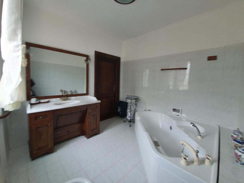 une salle de bain avec une baignoire, un lavabo et un miroir dans l'établissement Villa con piscina tra Versilia e Cinque Terre, à Luni