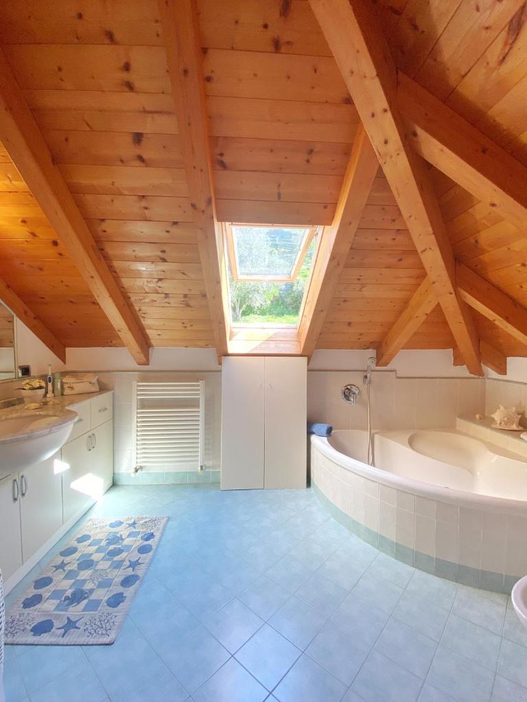 La salle de bains est pourvue d'un plafond en bois et d'une baignoire. dans l'établissement Appartamento Moneglia, à Moneglia