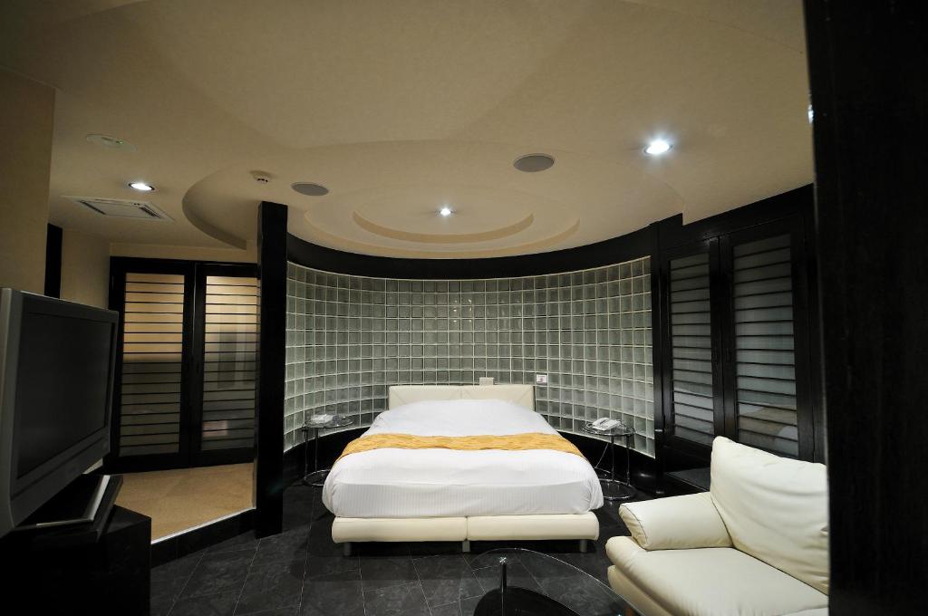 une chambre avec un lit, un canapé et une télévision dans l'établissement premium resort nagoya, à Nagoya