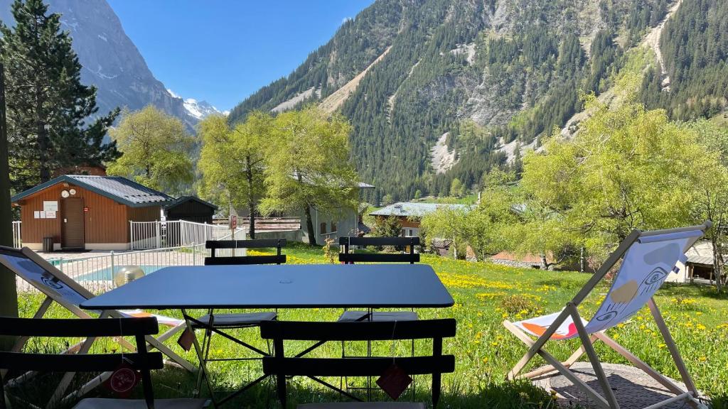 - une table de pique-nique et des chaises dans un champ avec des montagnes dans l'établissement Le Bouquetin 73 Appartement cosy type chalet avec piscine au pied des pistes et superbe vue panoramique, à Pralognan-la-Vanoise