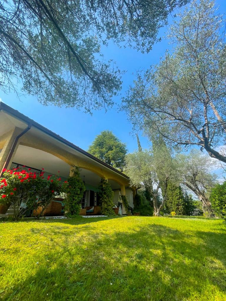 une maison avec une cour verdoyante à côté d'un bâtiment dans l'établissement Villa con vista lago e piscina, à Moniga del Garda