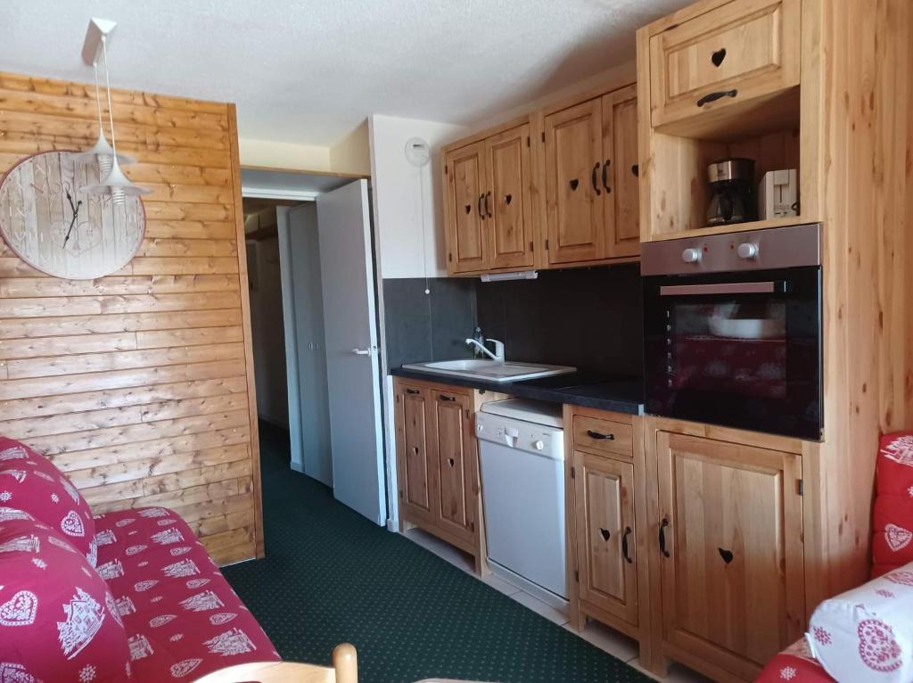 une cuisine avec des armoires en bois et un four à plaques de cuisson dans l'établissement appart entierement renové les coches - la Plagne, à Bellentre 10 autres photos