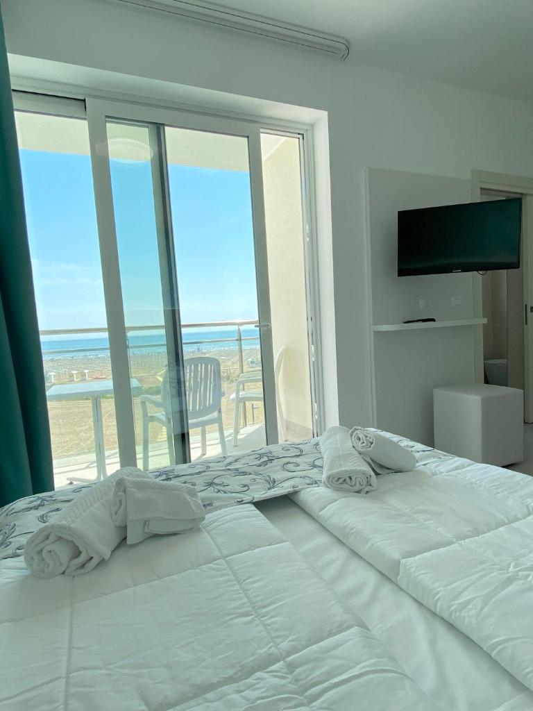 un grand lit blanc avec vue sur l'océan dans l'établissement Hotel Linda, à Caorle