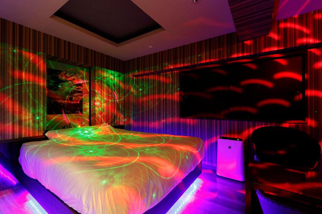 - une chambre avec un lit éclairé par des lampes de néon dans l'établissement 555MOTEL SHONAN, à Fujisawa