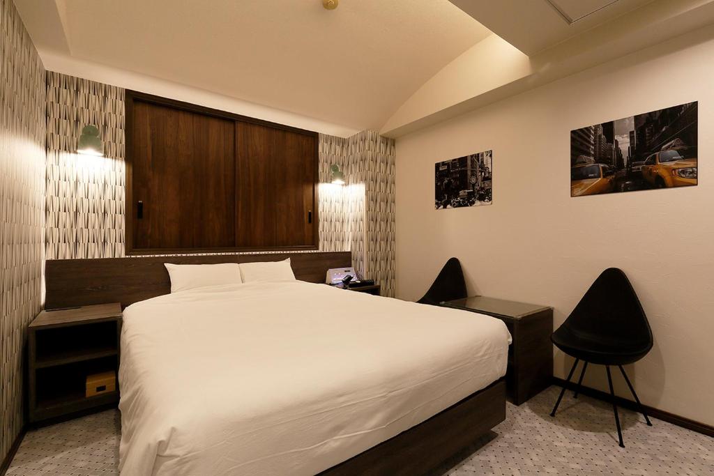 une chambre avec un grand lit et deux chaises dans l'établissement 555MOTEL SHONAN, à Fujisawa