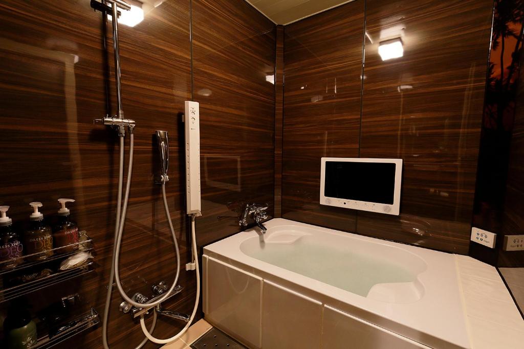 une salle de bain avec une baignoire et une télévision au mur dans l'établissement 555MOTEL SHONAN, à Fujisawa