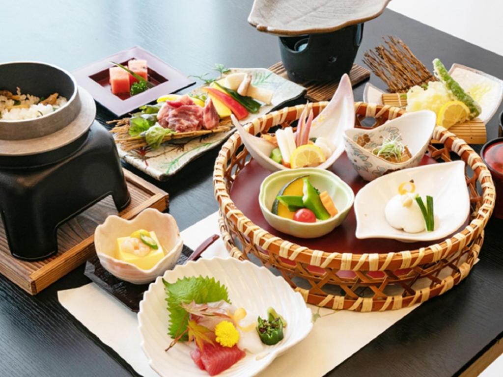 une table recouverte de assiettes et de bols de nourriture dans l'établissement LiVEMAX RESORT Sakurajima Sea Front, à Tarumizu