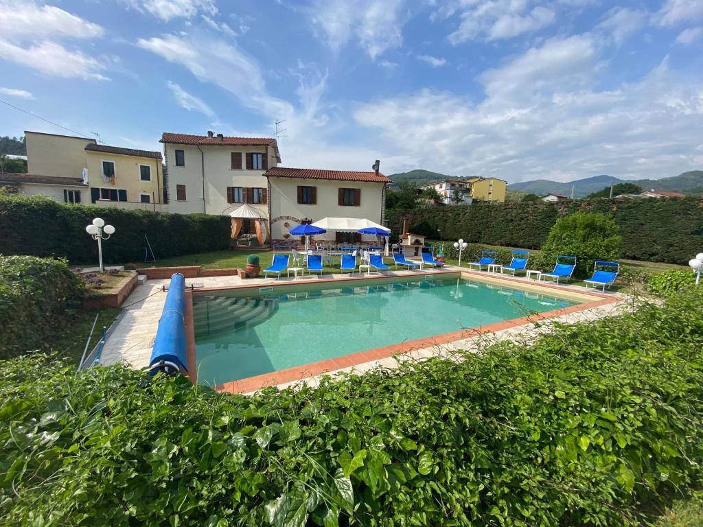 une grande piscine avec des chaises bleues et une maison dans l'établissement Villa con piscina tra Versilia e Cinque Terre, à Luni