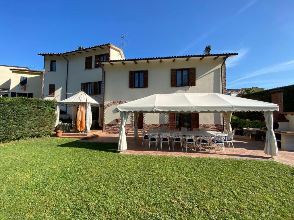 une table et des chaises sous une tente blanche en face d'une maison dans l'établissement Villa con piscina tra Versilia e Cinque Terre, à Luni