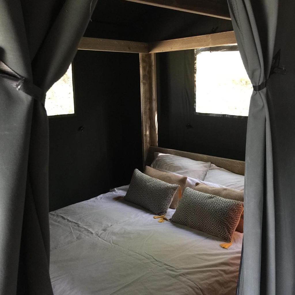 - une chambre avec un lit avec deux oreillers et une fenêtre dans l'établissement Safari tent lodges with a beautiful view at Lot Sous Toile, à Montamel 25 autres photos