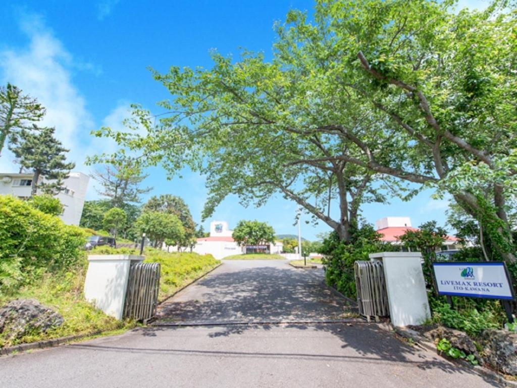 une allée avec des arbres et une porte au bout d'une route dans l'établissement LiVEMAX RESORT Ito Kawana, à Itō