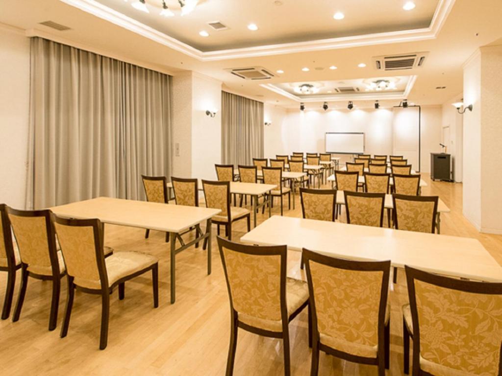 une salle de conférence avec des tables et des chaises et un podium dans l'établissement Spa Resort LiVEMAX, à Mooka