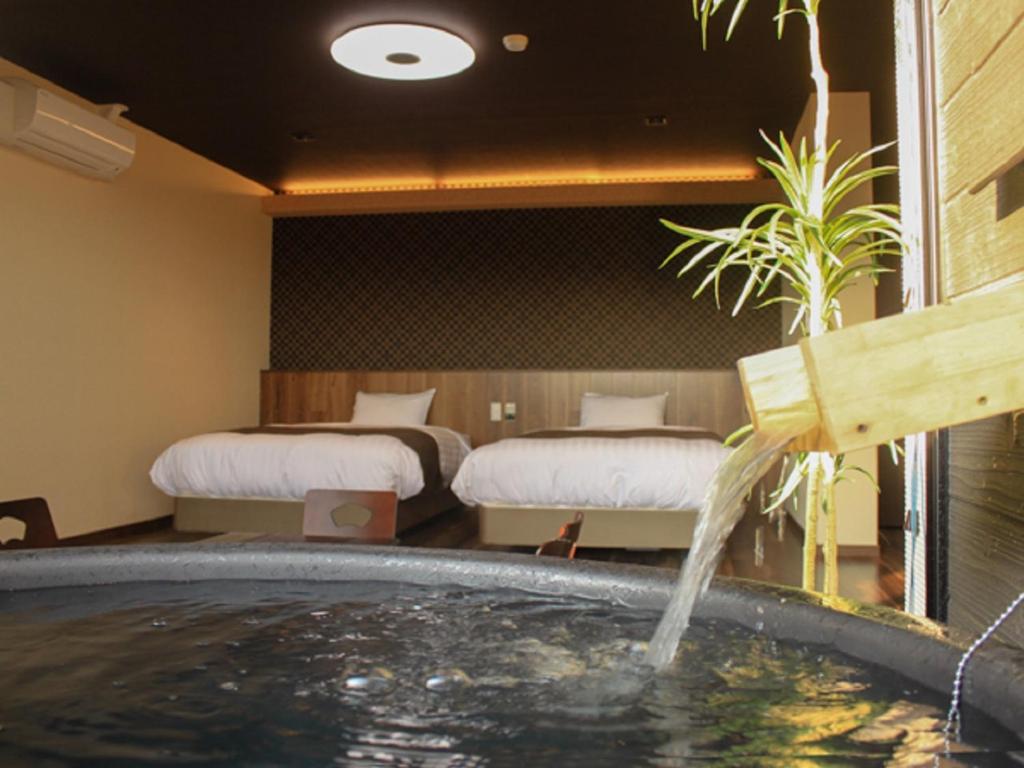 une chambre d'hôtel avec un bain à remous et 2 lits dans l'établissement LiVEMAX RESORT Kinugawa, à Nikkō