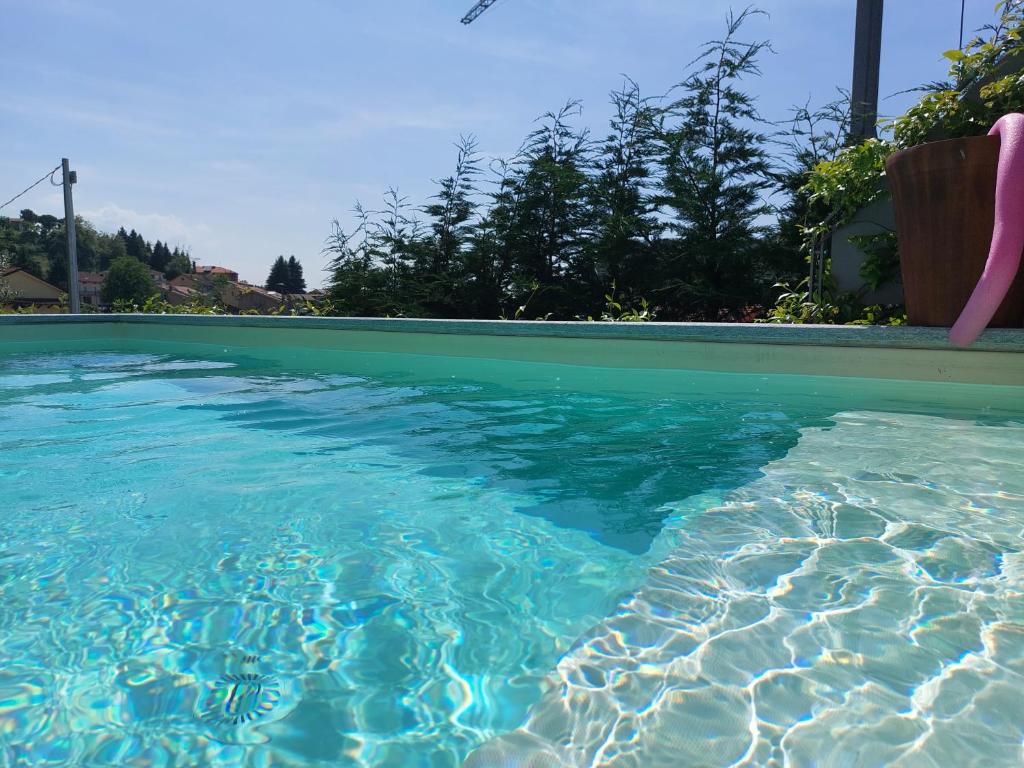 une piscine d'eau bleue claire avec une chaise dedans dans l'établissement Villa Monforte Barolo with private pool - LANGHE GATEWAY, à Monforte dʼAlba