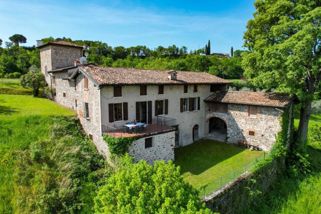 une ancienne maison en pierre sur une colline avec des arbres dans l'établissement Casale Lucrezia by Garda FeWo, à Salò