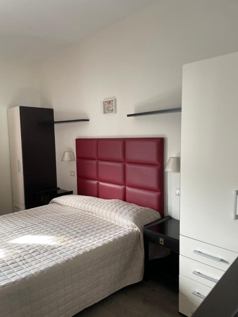 une chambre avec un grand lit avec une tête de lit rouge dans l'établissement Hotel Vera, à Cesenatico