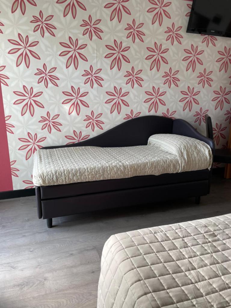 Ce lit se trouve dans une chambre dotée d'un papier peint fleuri. dans l'établissement Hotel Vera, à Cesenatico 24 autres photos