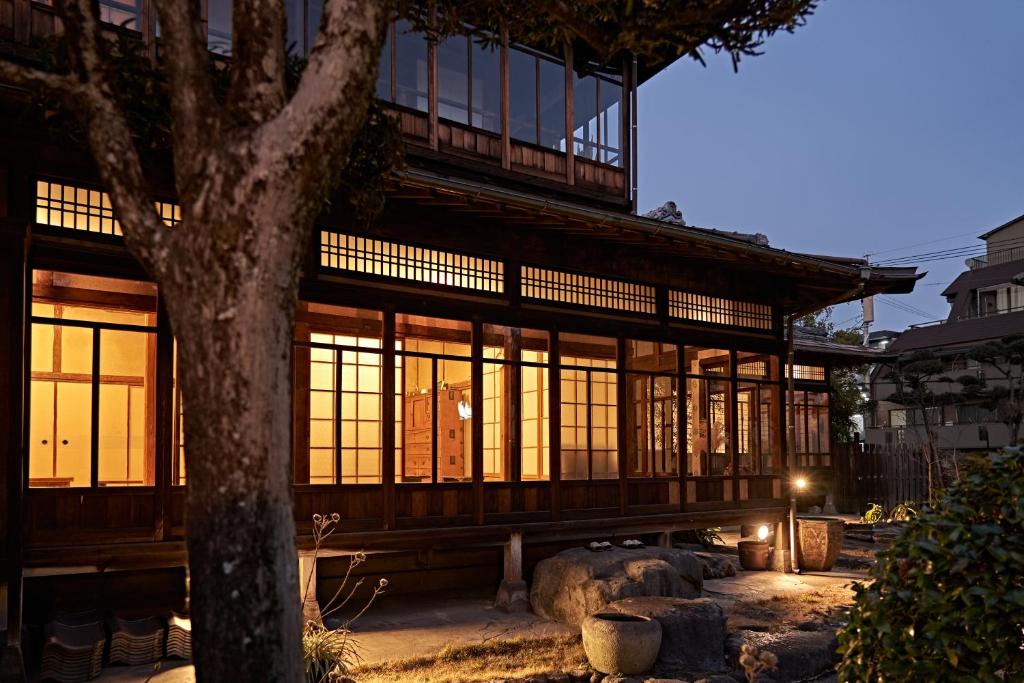 un grand bâtiment avec de grandes fenêtres et un arbre dans l'établissement Yamada Bessou くつろぎの温泉宿 山田別荘, à Beppu