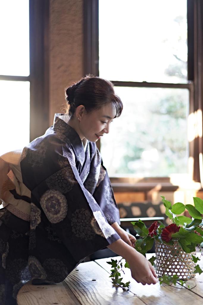 une femme en kimono assise à côté d'une table dans l'établissement Yamada Bessou くつろぎの温泉宿 山田別荘, à Beppu