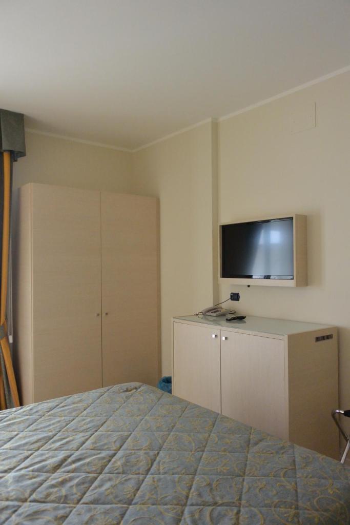 une chambre avec un lit et une télévision à écran plat dans l'établissement Hotel Columbus, à Lignano Sabbiadoro