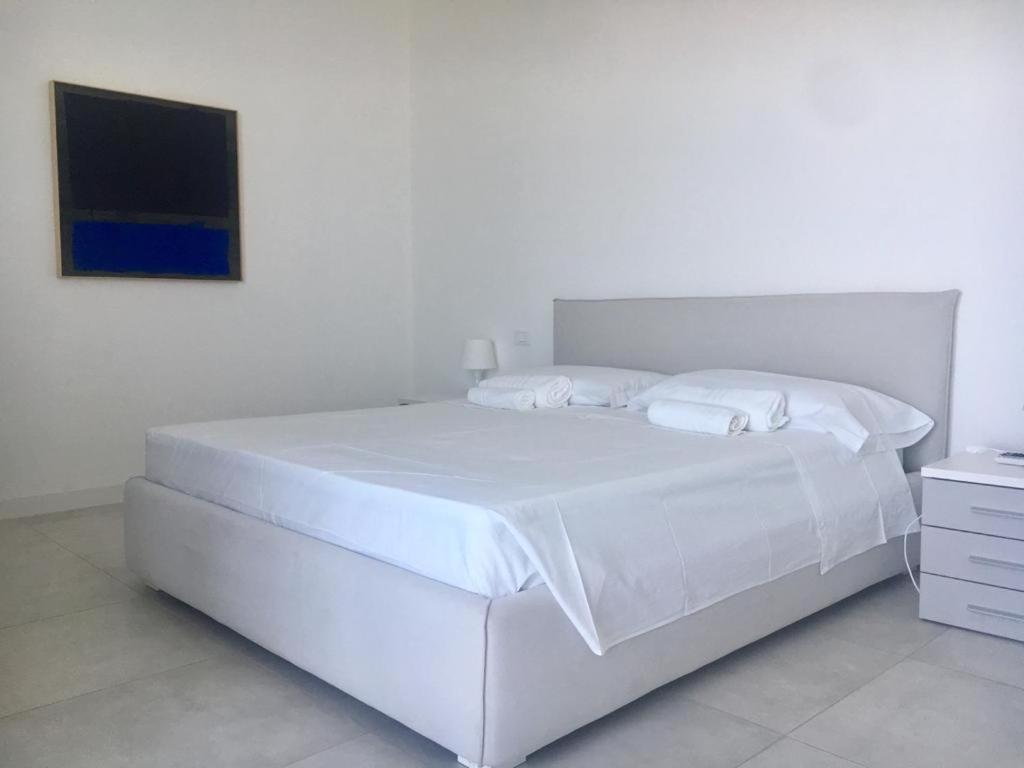 - un lit blanc avec des draps et des oreillers blancs dans l'établissement Luxury villa Blue&Blanc piscina a sfioro isola, à Diamante