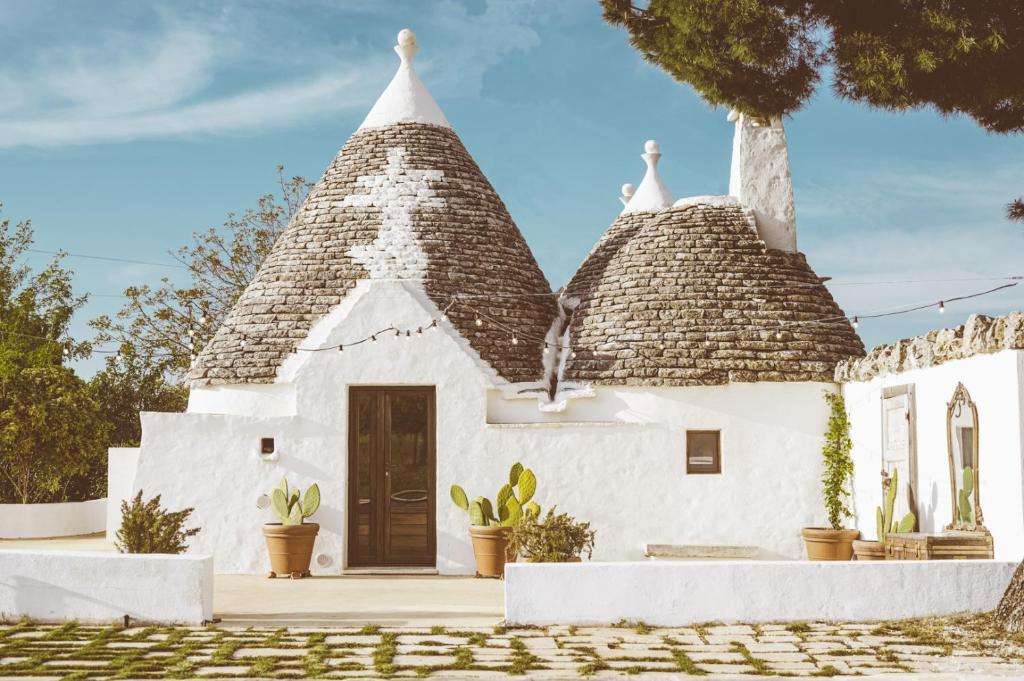une maison blanche avec deux toits de chaume dans l'établissement Trulli Difesa, à Martina Franca
