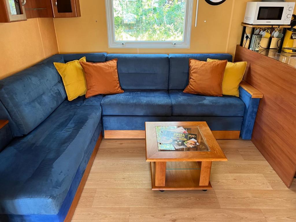 un canapé bleu dans un salon avec une table dans l'établissement Joli Mobil-Home de Vacances, Ideal pour les familles, à Rocbaron 11 autres photos