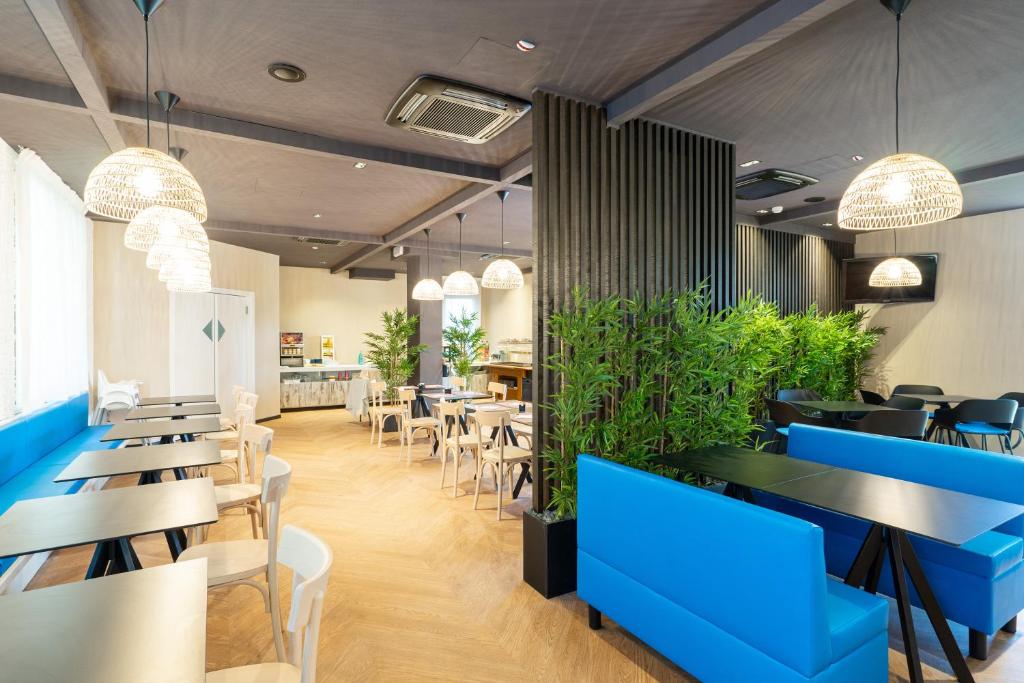 un restaurant avec des tables bleues, des chaises et des plantes dans l'établissement B&B Isabella, à Milano Marittima