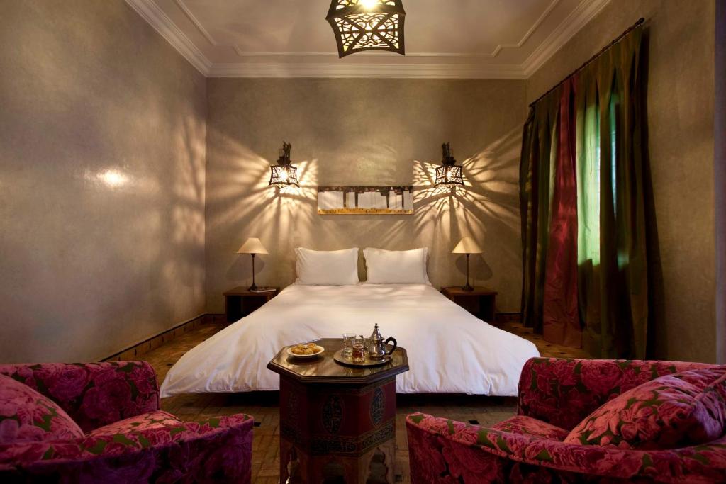 une chambre avec un lit blanc et deux chaises dans l'établissement Riad Les Bougainvilliers, à Marrakech