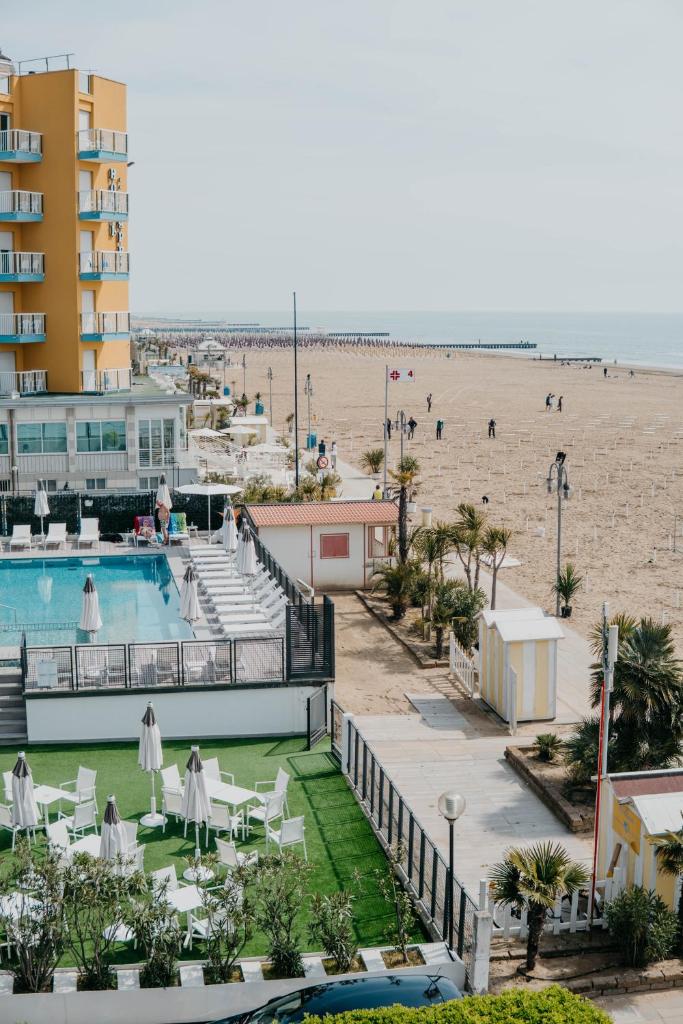 un complexe avec piscine et plage dans l'établissement Hotel Adlon, à Lido di Jesolo