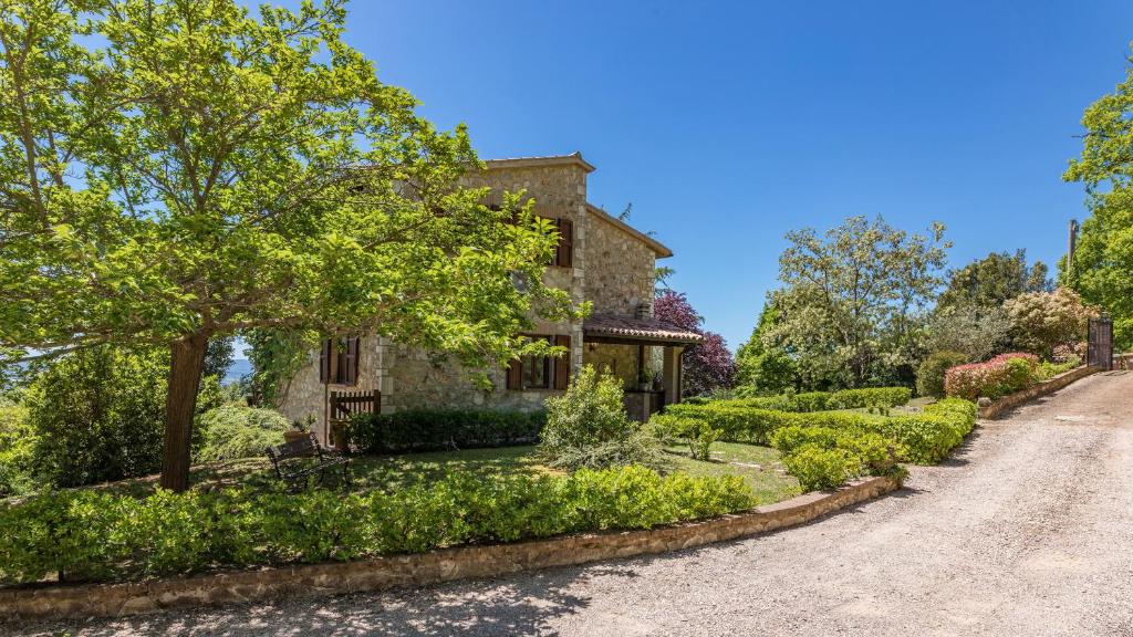une maison en pierre avec un jardin en face d'une allée. dans l'établissement Villa Paola 6, Emma Villas, à Gualdo Cattaneo