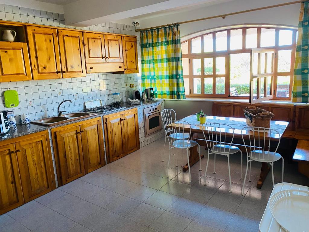 une cuisine avec des armoires en bois et une table et des chaises dans l'établissement Villa Carmen con piscina, à Syracuse