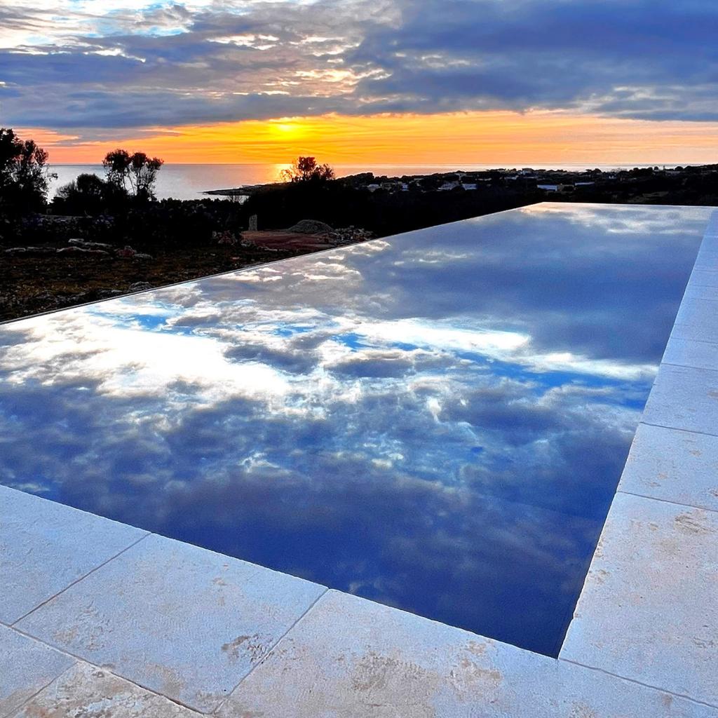 une piscine d'eau avec un coucher de soleil dans le ciel dans l'établissement Villa CREA, à Marina di Leuca