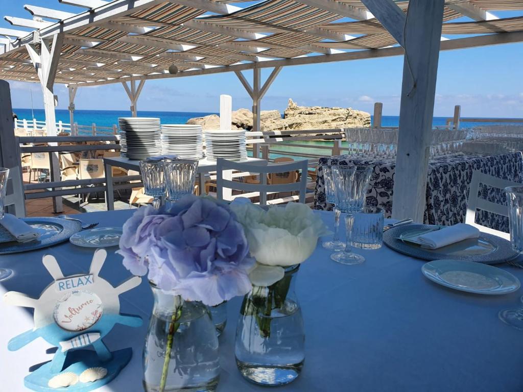une table avec des assiettes bleues et des vases avec des fleurs dans l'établissement Oldwell Hotel, à Santa Domenica