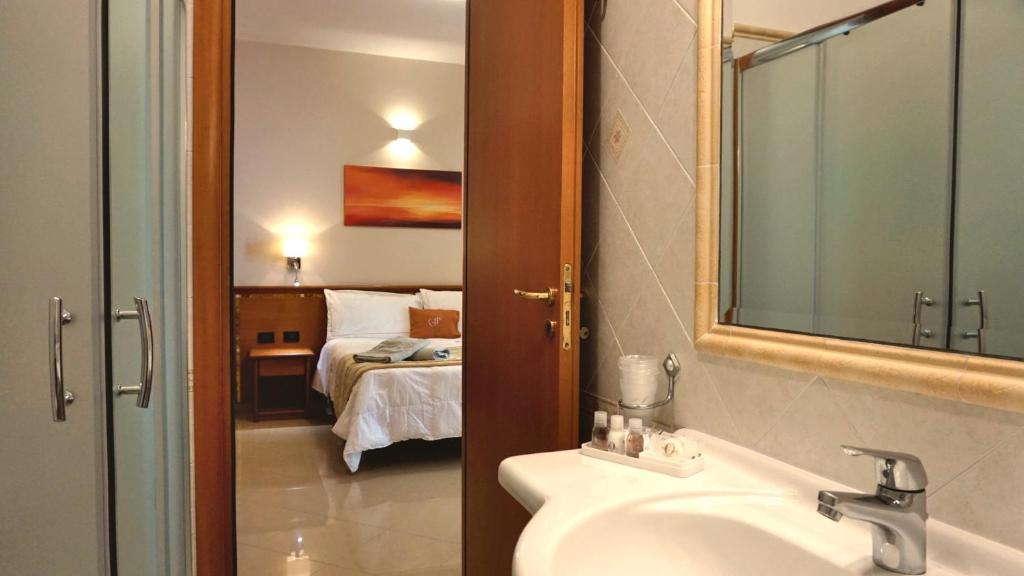 une salle de bain avec un lavabo et une chambre avec un lit dans l'établissement Hotel Residence Piccolo, à Parghelia