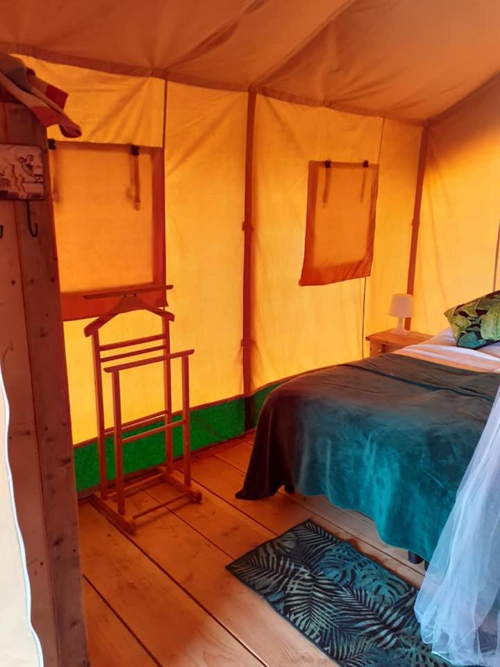 - une chambre avec un lit et une chaise dans une tente dans l'établissement Luxe safarilodgetent met boxspring bedden, à Montcléra