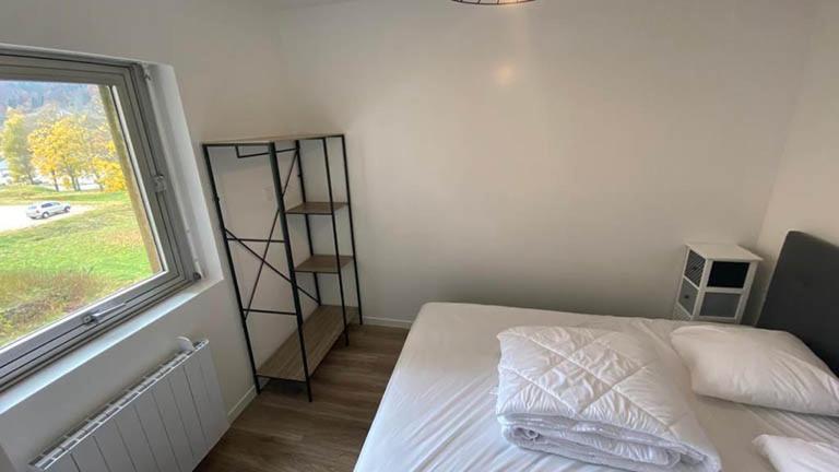 une chambre blanche avec un lit et une fenêtre dans l'établissement Lelexine, à Lélex