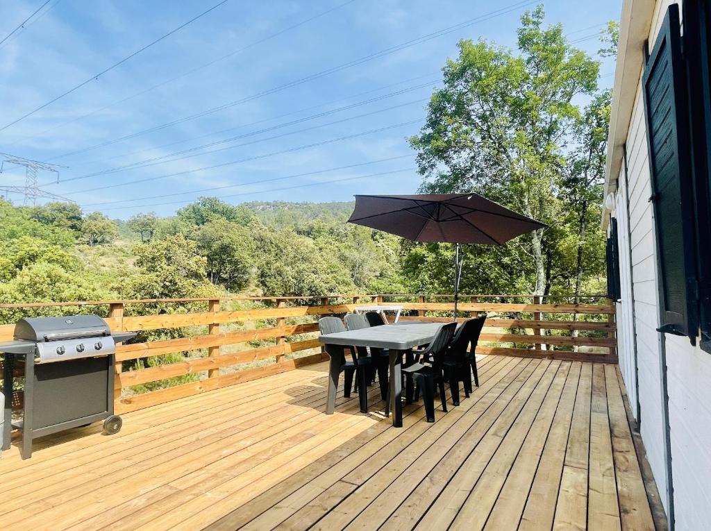 une table et des chaises sur une terrasse avec un parasol dans l'établissement Charmant Chalet avec terrasse et accès piscine., à Rocbaron