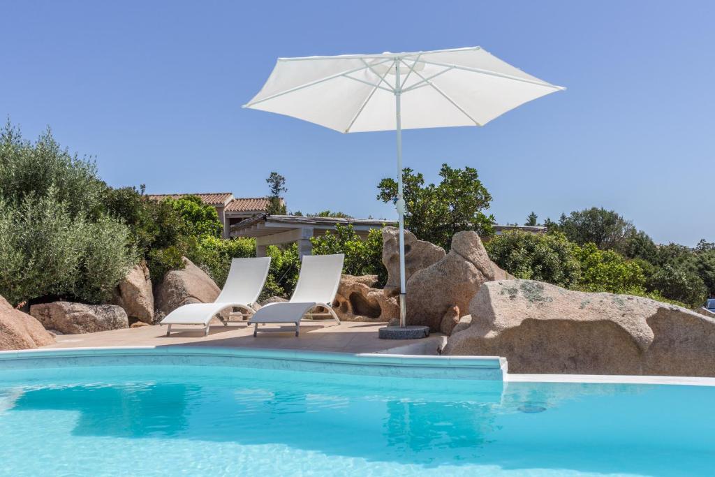 - une piscine avec 2 chaises et un parasol dans l'établissement villa Le farfalle, à San Teodoro