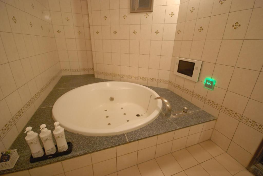 La salle de bains est pourvue d'une baignoire avec 2 bouteilles sur un comptoir. dans l'établissement HOTEL WiLL EX 大高 レジャーホテル, à Nagoya