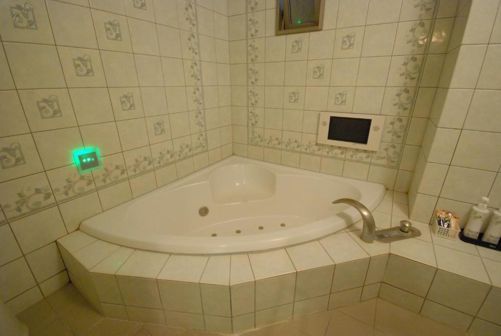 La salle de bains est pourvue d'une baignoire et de lumière verte. dans l'établissement HOTEL WiLL EX 大高 レジャーホテル, à Nagoya