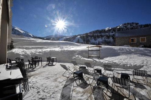 un groupe de chaises et de tables dans la neige dans l'établissement Hotel Le Druos, à Isola 2000